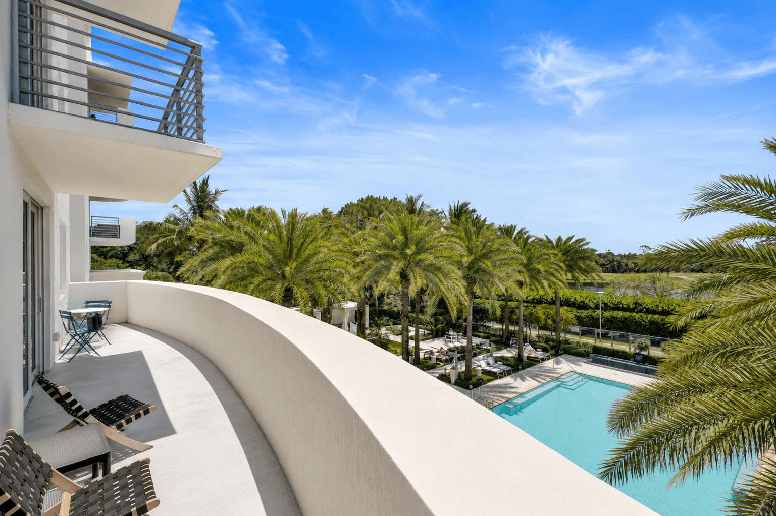 A modern building with a pool and palm trees in the background.